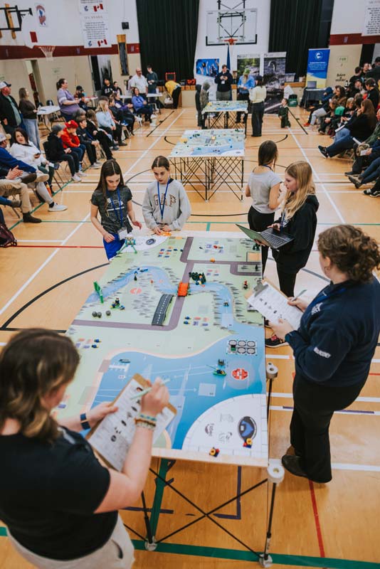 Competition time! Trudy Mulrooney and Natalie Poole of the Clarenville High School EcoSTEM team (bottom) judge one of the 14 teams during the competition phase at Riverside Elementary near Clarenville, NL.