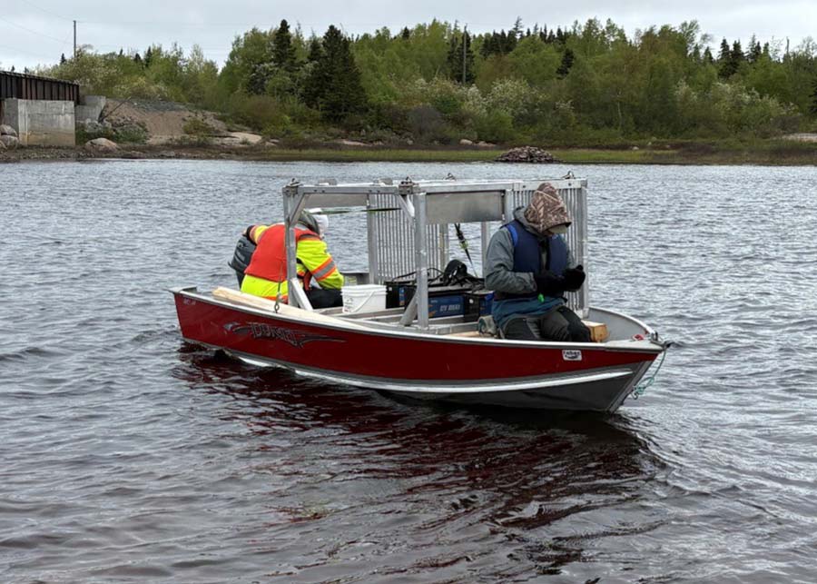 Sean Jackson (left) of FABEC and Jordan Condon set off downriver in <i>Johnny’s Dream</i> with the new cage for the RiverWatcher. The cage and RiverWatcher each weigh several hundred pounds, so getting them downriver and across a kilometer of boggy ground was no small feat. Photo: Kris Hunter
