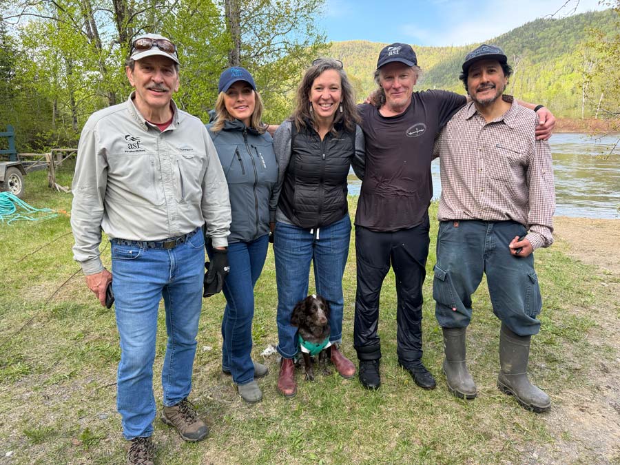 De gauche à droite : Charles, Deirdre, Eveline, Jon, et Pedro (MPO) se rassemblent au bord de la rivière après que la roue à saumoneaux eut été solidement amarrée à la rive. <br>Photo : Martin Silverstone.